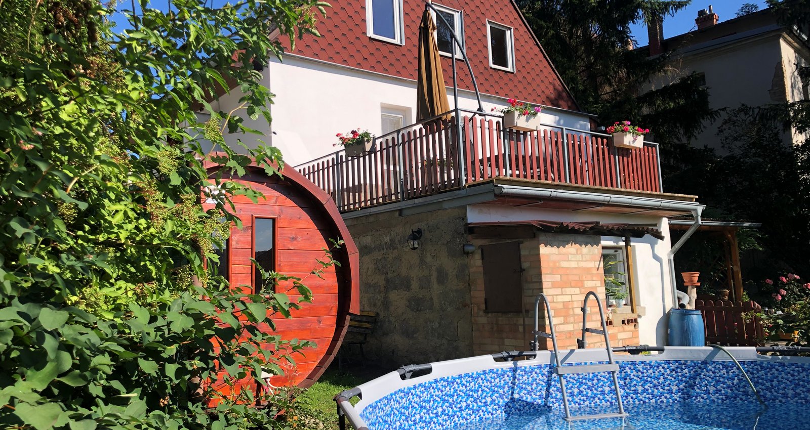 Umzunter Garten mit Entspannungsbereich mit Sonnenliegen, Schwimmbad, Rucherkammer und stilvoller Blockhaussauna.